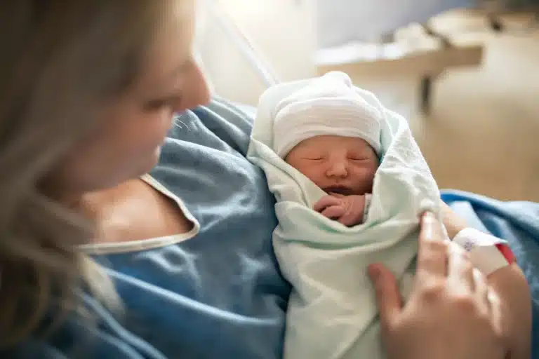 bébé qui dort dans les bras de sa mère à la maternité